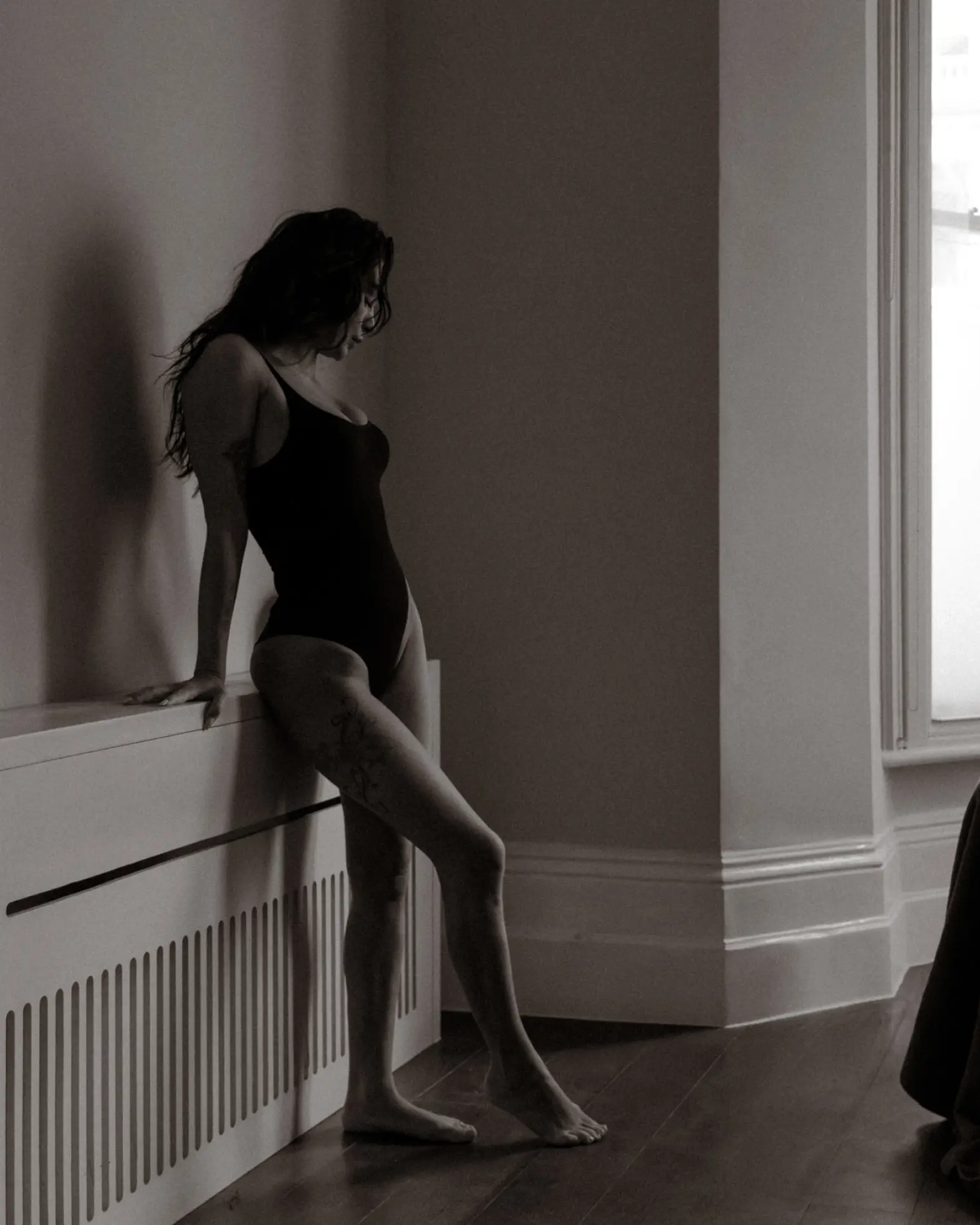 Moody photograph of a woman leaning against a wall in soft light